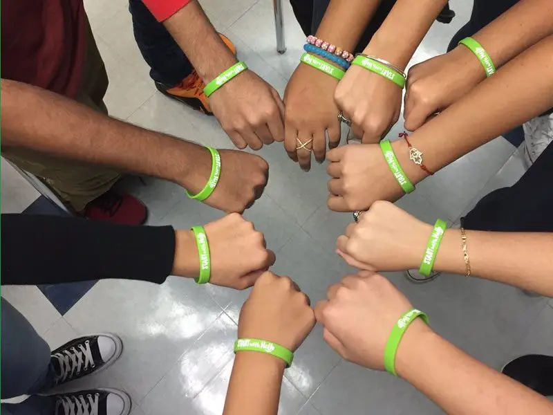 Hands in a circle with Start With Hello bracelets