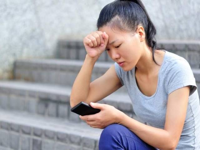 Student in distress looks at her phone.