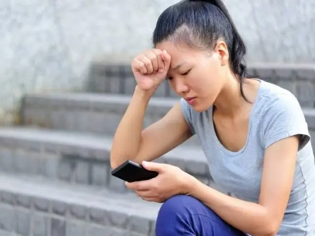 Student in distress looks at her phone.