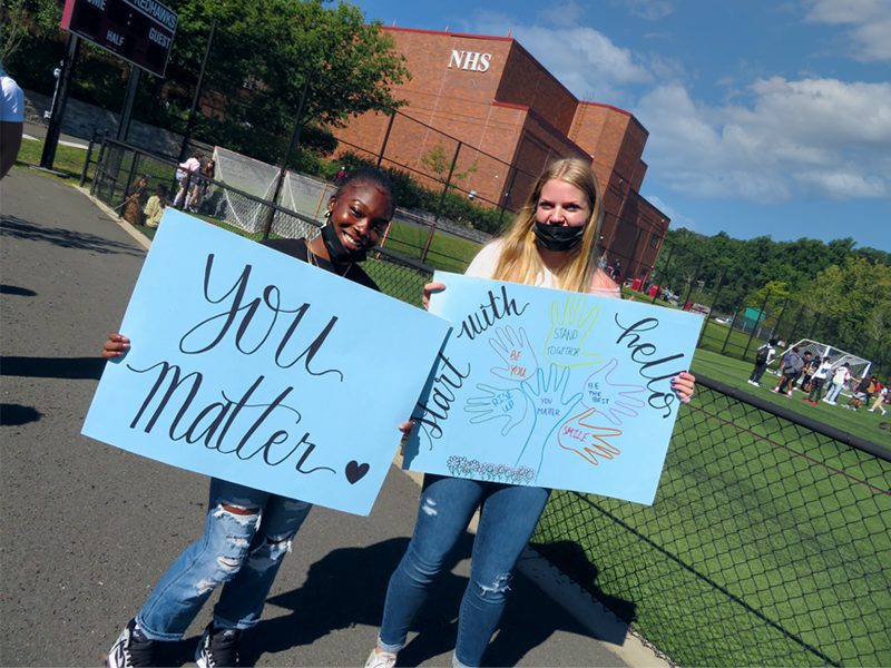 Two students holding "you matter" and "Start With Hello" signs