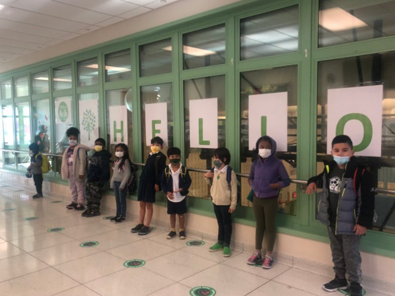 Group of elementary student in front of "Hello" sign.