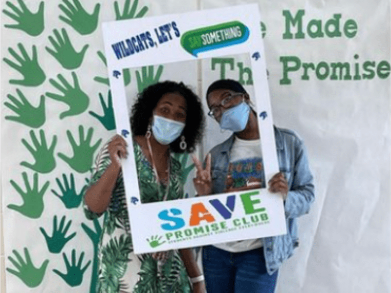 Student and aducator holding a SAVE Promise club selfie frame