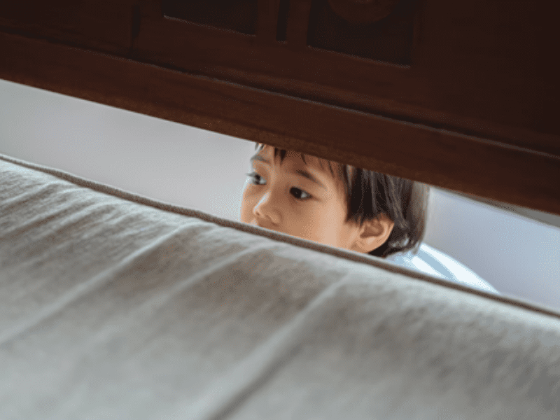 Toddler peeking through furniture
