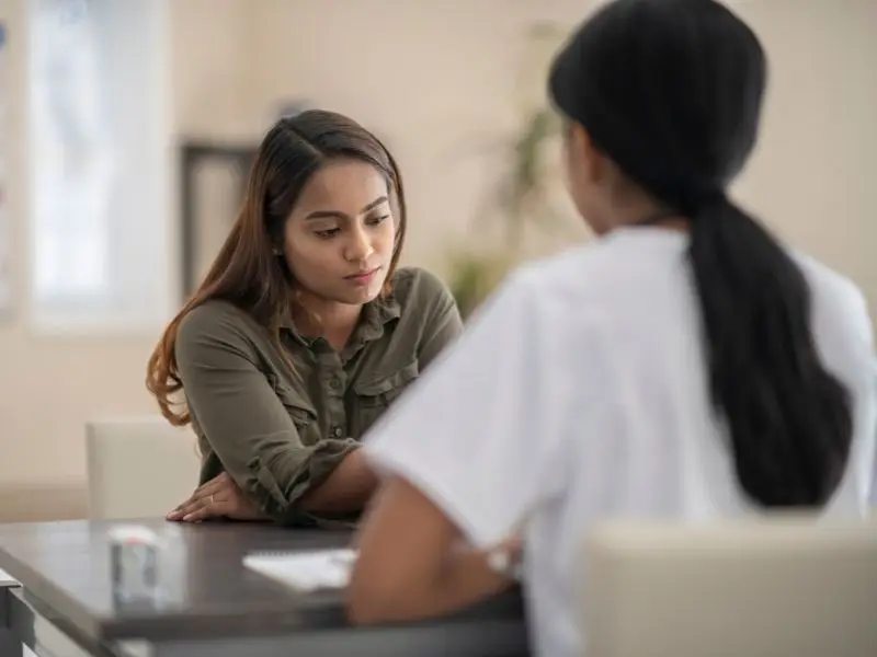 Young female struggles with depression at medical appointment.
