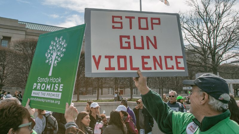 A man holding a sign that says "Stop Gun Violence".
