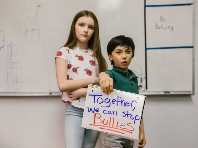 Two students holding up a sign with the words "Together we can stop bullying"