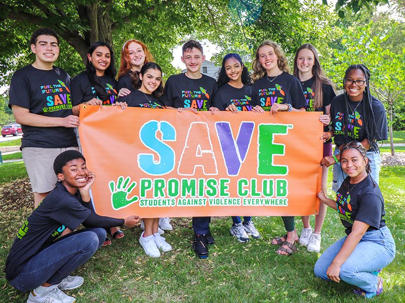 SAVE Promise Club holding a large sign