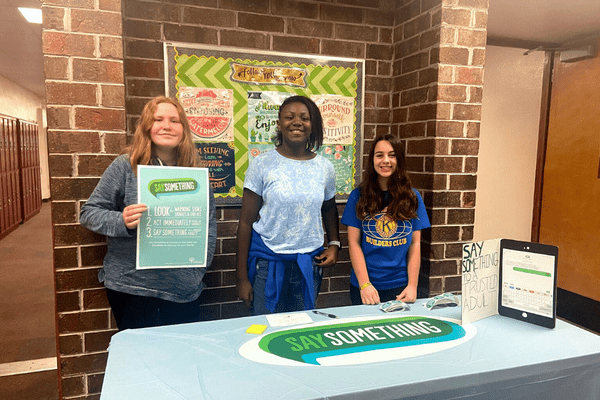 Students promoting Say Something on a table at their shcool