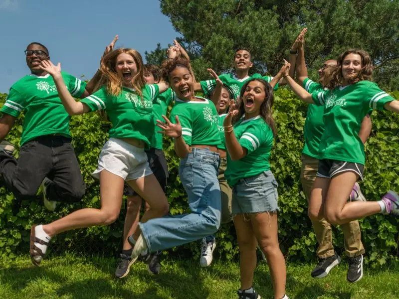 Group of students jumping and wearing Sandy Hook Promise green t-shirts.