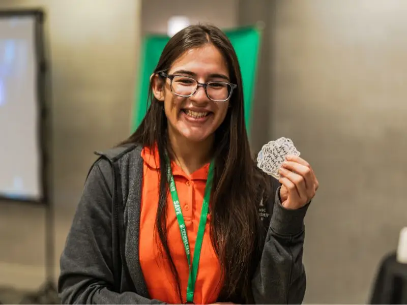 Kristina Alzugaray wearing SAVE orange shirt and holding stickers at the YAB Summer institute.