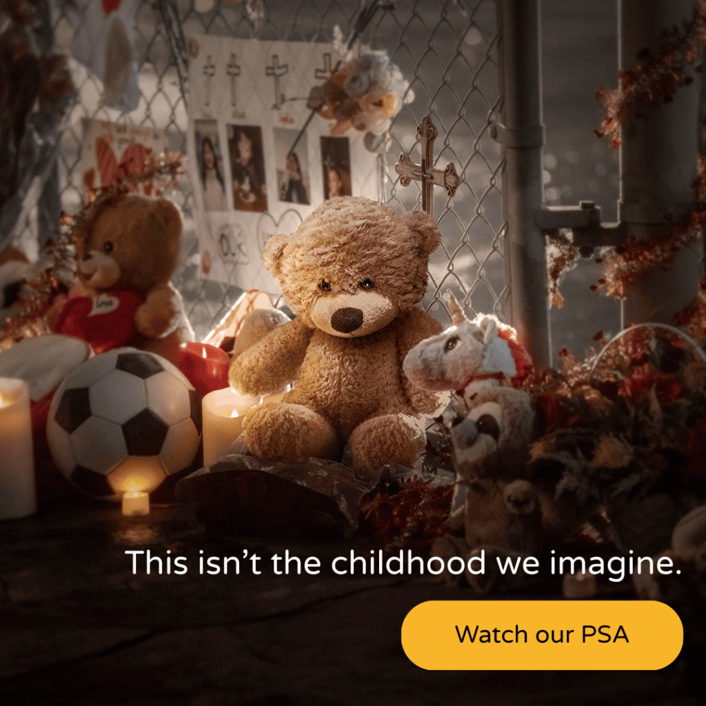 A memorial shrine with a teddy bear, toys, poster, and candles.