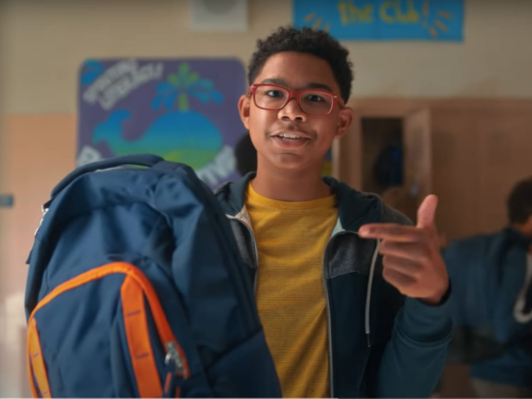 Student holds up a backpack in a school hallway, highlighting a back-to-school essential in the Sandy Hook Promise Back-to-School Essentials PSA.