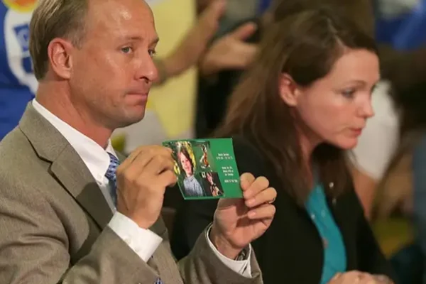 Mark Barden and Nicole Hockley sitting together. Mark is holding a photo.